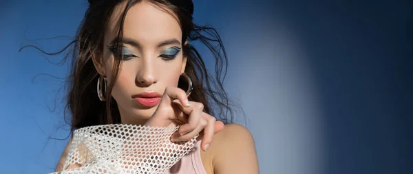 Модная молодая азиатская модель с макияжем и прической на синем фоне, баннер — стоковое фото