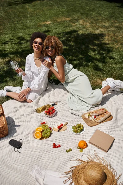 Picnic de verano de novias afroamericanas cerca de frutas y verduras frescas en el parque - foto de stock