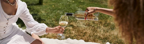 Partial view of african american girlfriends pouring wine on summer picnic, banner — Stock Photo