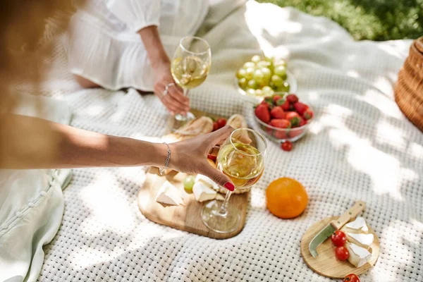 Vista recortada de las mujeres afroamericanas con copas de vino cerca de aperitivos en el picnic de verano - foto de stock