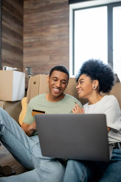 Compiaciuta coppia afro-americana fare shopping online vicino a pacchetti in soggiorno a casa — Foto stock