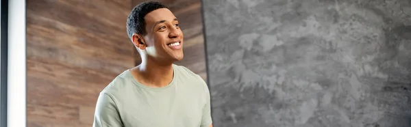 Happy and smiling african american man looking away while standing in new house, banner — Stock Photo