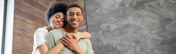 Gioiosa donna afroamericana che abbraccia il fidanzato sorridente in una nuova casa, striscione — Foto stock