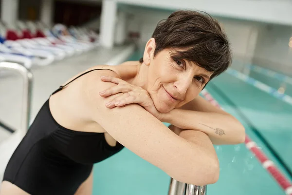 Portrait of middle aged sportswoman with tattoo, mature woman, swimming pool, spa center, resort — Stock Photo