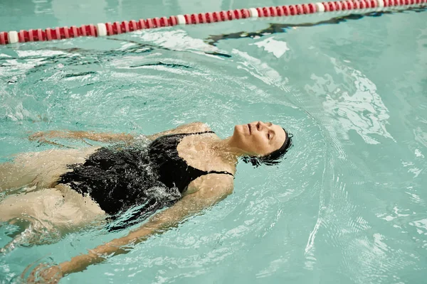 Спокойствие, женщина средних лет, купание на спине в бассейне, плавательная шапочка и очки, спорт, здоровый образ жизни — стоковое фото