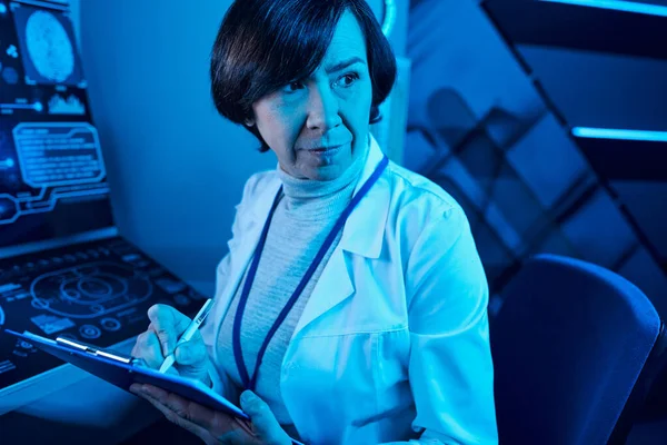 Futuristic Expertise: Senior Woman Scientist Records Data and Contemplates in Future Science Center — Stock Photo