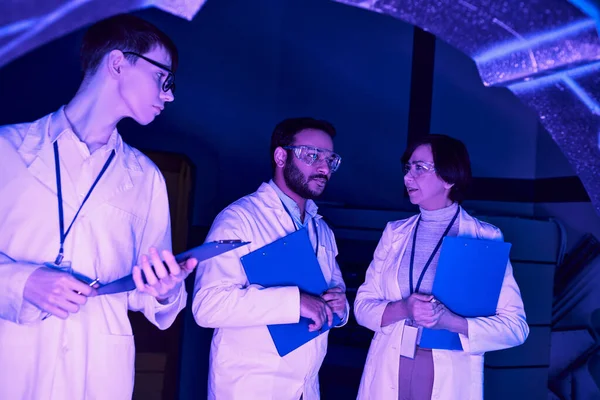 Collaborazione futuristica: gli scienziati di varie epoche convergono nel centro scientifico Neon-Lit — Foto stock