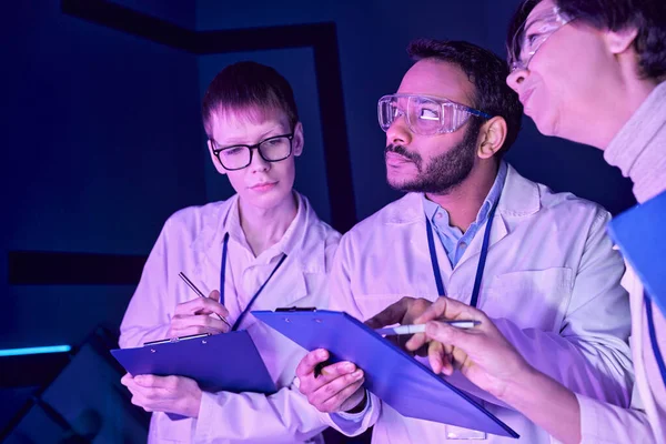 Futuristic Collaboration: Multigenerational Scientists Work Together in Neon-Lit Science Center — Stock Photo