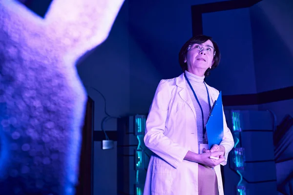 Regard futuriste : Une femme examine le dispositif nouvellement créé dans le centre scientifique de demain — Photo de stock