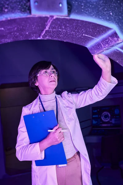 Centre scientifique futuriste, femme scientifique avec presse-papiers examinant dispositif innovant — Photo de stock