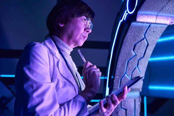 Technologies futures, femme scientifique réfléchie avec stylo explorant l'équipement expérimental — Photo de stock