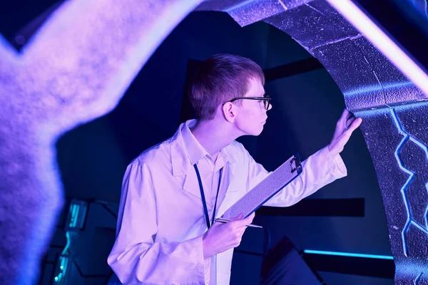 Future technologies, young intern with clipboard examining new equipment in science center — Stock Photo