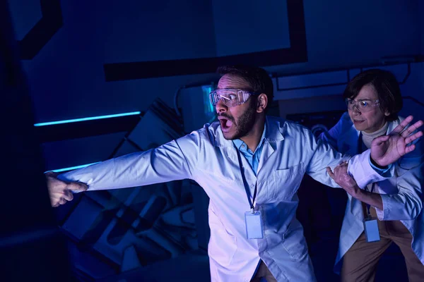 Exploring future, shocked multiethnic scientists near hand appearing from experimental device — Stock Photo