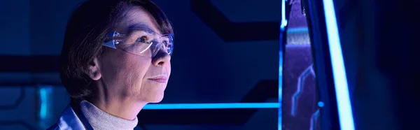 Tecnologías futuristas, mujer de mediana edad científica en gafas examinando dispositivo innovador, pancarta - foto de stock