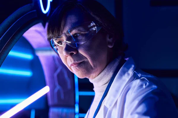 Retrato de mujer científica de mediana edad en gafas en el centro de ciencia, con visión de futuro - foto de stock