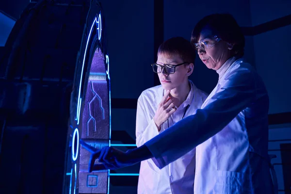 Centro de innovación, mujer científica operando equipo nuevo cerca de joven interno en el centro de ciencia - foto de stock