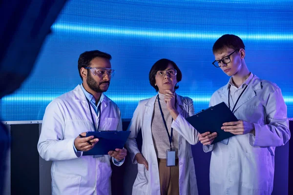Concept futuriste, équipe multiethnique de scientifiques avec presse-papiers travaillant dans un centre d'innovation — Photo de stock