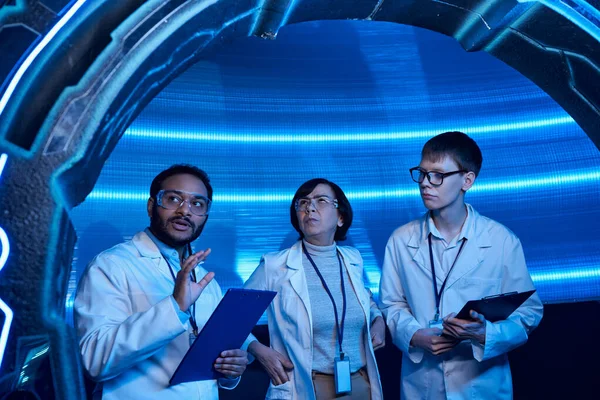Futuristic invention, indian scientist talking near colleagues and new device in science center — Stock Photo