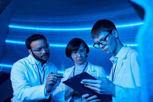 Advanced learning, indian scientist pointing at clipboard near young intern in discovery center — Stock Photo