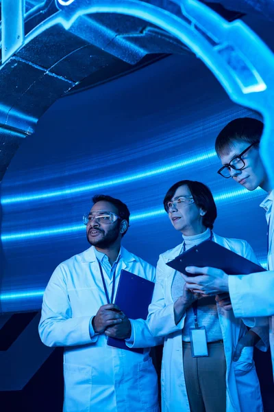 Futuristic research, multiethnic scientists examining experimental device in innovation hub — Stock Photo