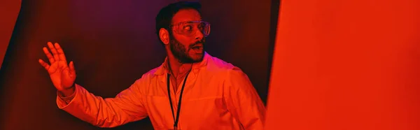 Frightened indian scientist looking away in red neon light, unknown phenomenon, banner — Stock Photo