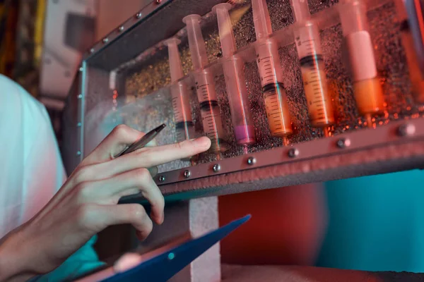 Vista recortada del científico apuntando a los tubos de ensayo con muestras líquidas de vida extraterrestre, exploración cósmica - foto de stock