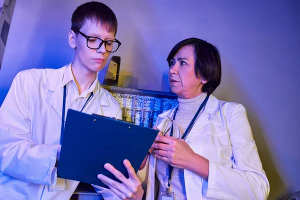 Woman scientist and young intern working on otherworldly exploration in innovation laboratory — Stock Photo