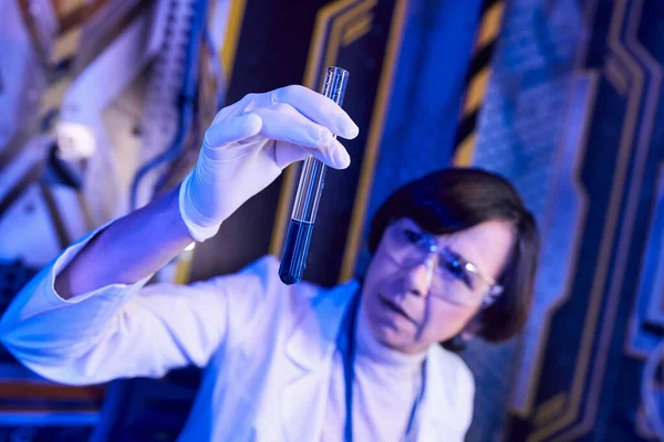 Donna scienziata sfocata in guanto di lattice con campione liquido in provetta in laboratorio di innovazione — Foto stock