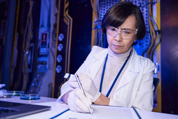 Ciência futura, mulher cientista escrevendo em prancheta perto de amostras extraterrestres em placas de Petri — Fotografia de Stock
