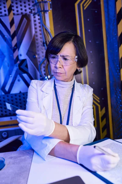 Explorant l'univers, femme scientifique en lunettes regardant le papier litmus en laboratoire expérimental — Photo de stock