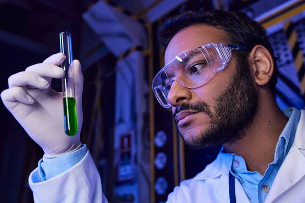 Исследуя вселенную, индийский ученый в очках держит пробирку с жидким образцом в лаборатории — стоковое фото