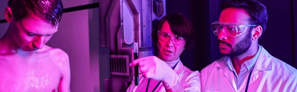 Científico sosteniendo probeta con muestra de sangre alienígena cerca de colega indio en laboratorio futurista, pancarta - foto de stock