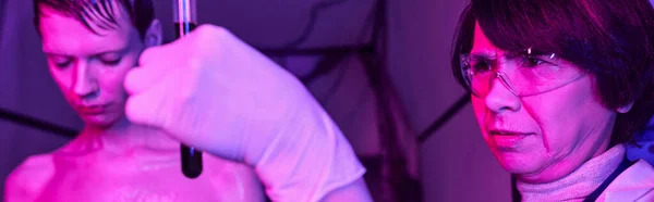 Женщина-ученый держит пробирку с образцом крови рядом с инопланетянином в научном центре, баннер — стоковое фото