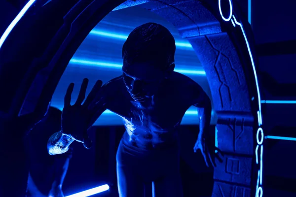 Cosmic phenomenon, extraterrestrial humanoid near experimental equipment in neon-lit science center — Stock Photo