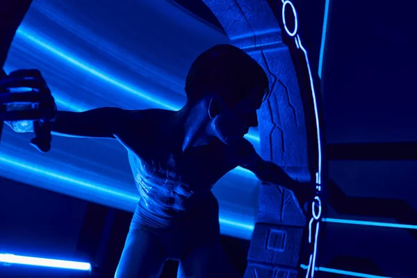Scoperta scientifica, umanoide ultraterreno vicino a un dispositivo innovativo nel laboratorio futuristico illuminato al neon — Foto stock