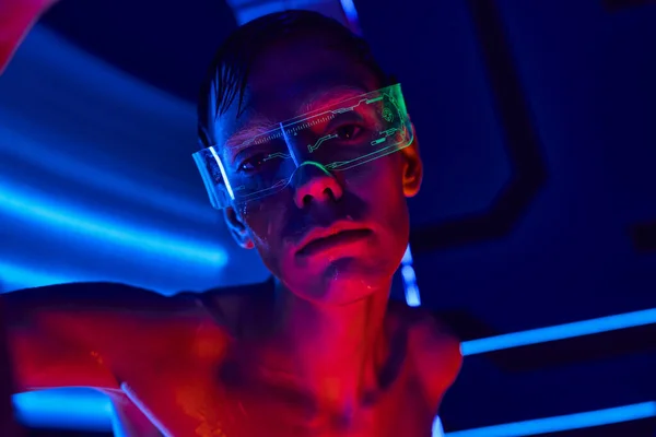 Cosmic traveler, unidentified humanoid alien in goggles looking at camera in neon-lit lab laboratory — Stock Photo