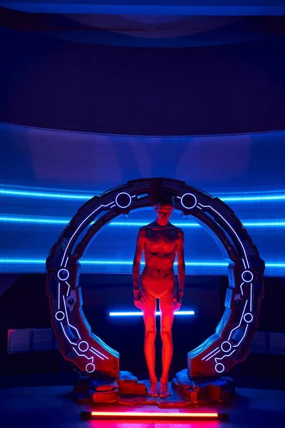 Внеземной гуманоид, стоящий в неоновом освещении инновационного устройства в футуристической лаборатории, полной длины — стоковое фото