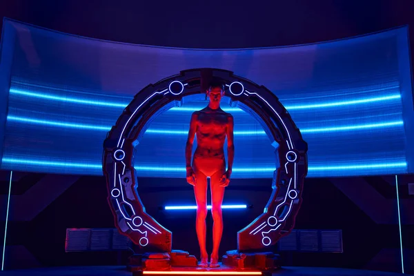 Invención científica, humanoide de otro mundo en dispositivo neón-iluminado en laboratorio futurista, longitud completa - foto de stock