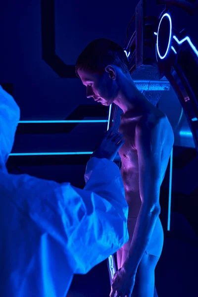 Fenomeno cosmico, scienziato in tuta hazmat toccare umanoide alieno in neon illuminato innovazione hub — Foto stock