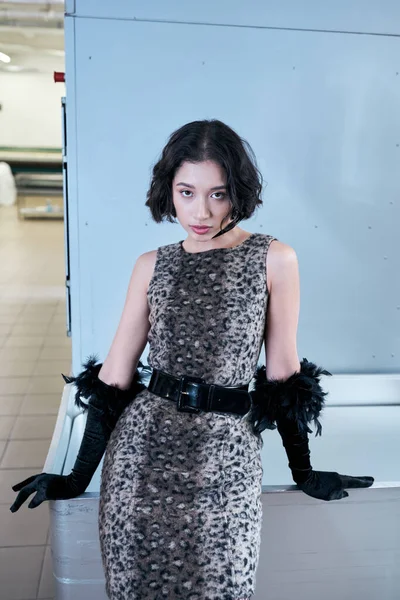 Junge asiatische Frau in Kleid und Handschuhen schaut in die Kamera, während sie in der öffentlichen Wäsche posiert — Stockfoto