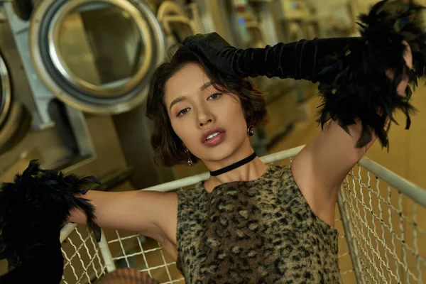 Retrato de mulher asiática na moda no vestido olhando para a câmera no carrinho na lavanderia pública — Fotografia de Stock
