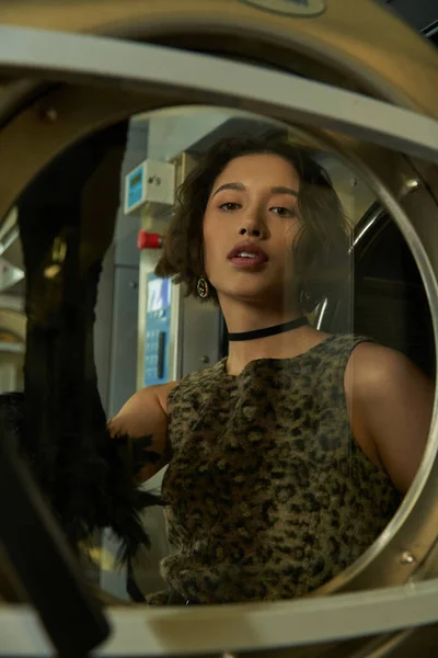 Модна молода азіатська жінка стоїть за склянкою пральної машини в монетному пральні — стокове фото