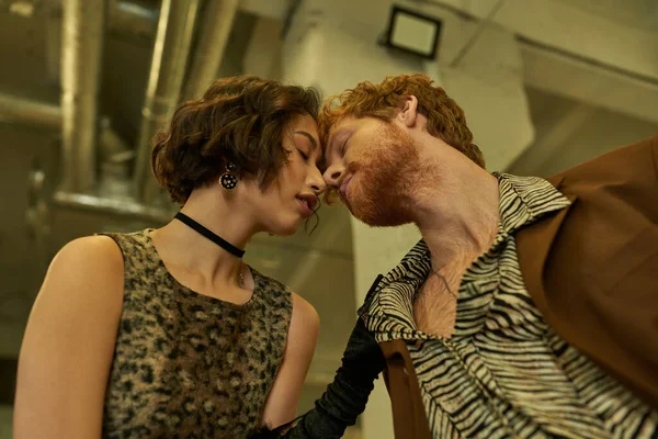 Низкий угол зрения стильная межрасовая пара поцелуи в общественном прачечной вечером — стоковое фото