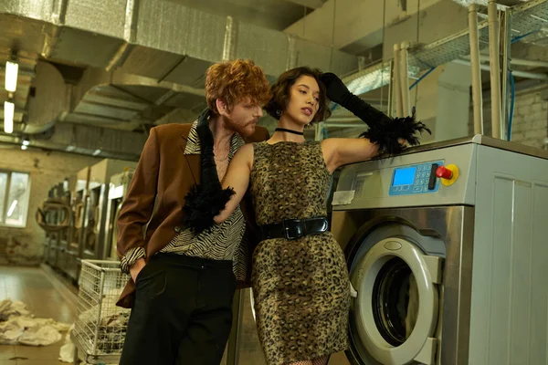 Сексуальний і стильний молодий чоловік фліртує з азіатською дівчиною в одязі в громадському пральні — стокове фото
