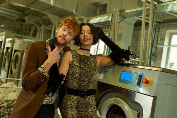 Élégant jeune asiatique femme en robe toucher rousse copain près de machine à laver dans la buanderie publique — Photo de stock