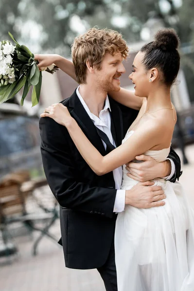 Interracial newlyweds in elegant attire embracing on street, outdoors wedding, banner — Stock Photo