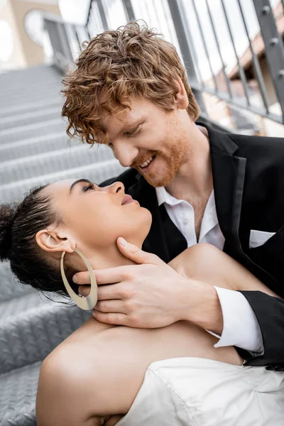 Romance urbano, casamento, ternura, noivo ruivo feliz abraçando noiva americana africana elegante — Fotografia de Stock
