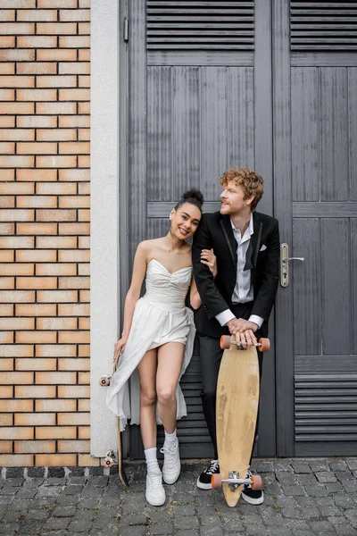 Paar in Hochzeitskleidung mit Longboard und Skateboard in der Nähe von Wohnungstüren — Stockfoto