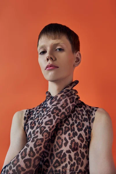 Concepto de moda queer, joven posando sobre fondo naranja, estampado animal sin mangas, estampado de leopardo - foto de stock