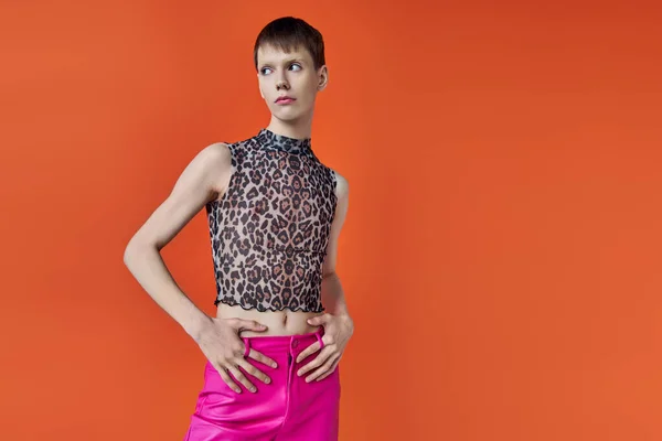 Concepto de moda, queer, joven posando sobre fondo naranja, impresión animal, estampado de leopardo, elegante - foto de stock